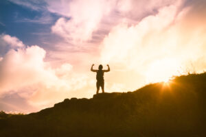 strong determined young personon top of mountain celebrating success