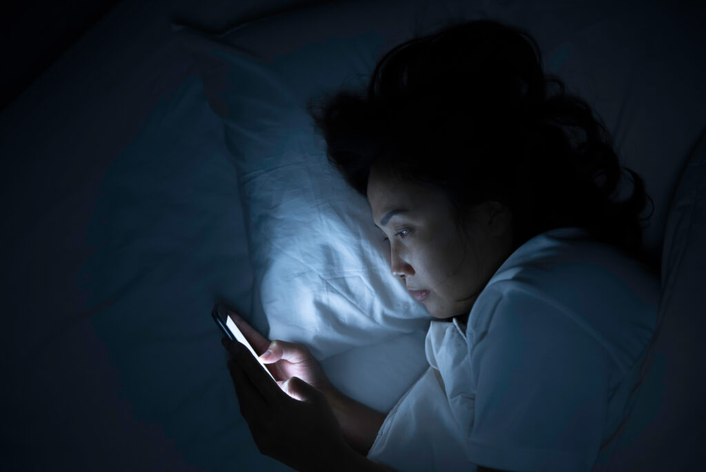Woman looking at smartphone in bed at night.