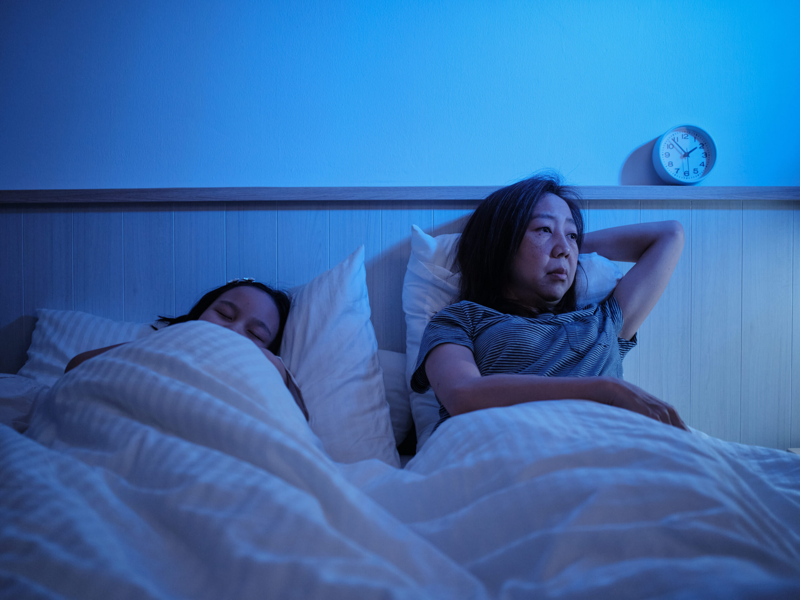 A woman lying in bed awake at night with anxiety and insomnia.